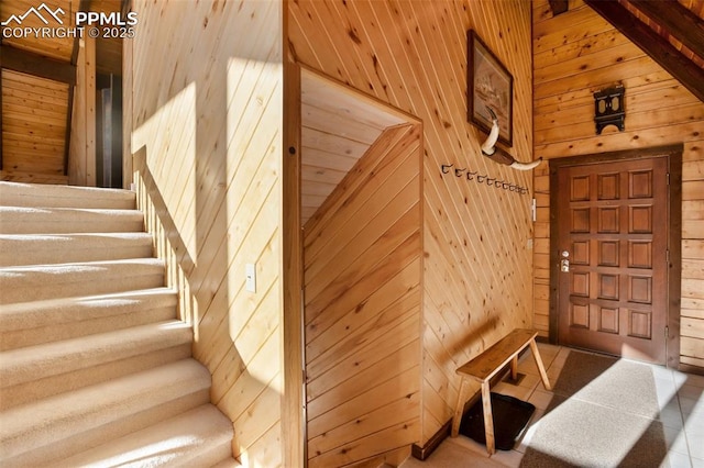 staircase featuring a high ceiling and wood walls