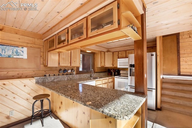 kitchen with white appliances, stone countertops, wooden walls, and log walls