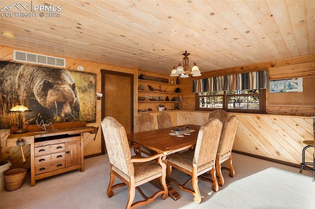 carpeted dining space with wood ceiling, wooden walls, and a chandelier