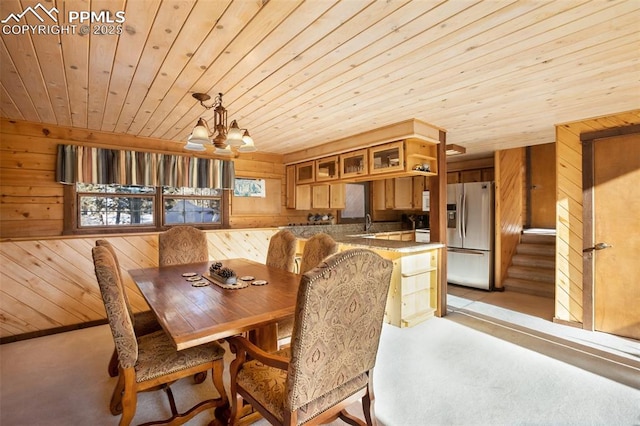 dining room with an inviting chandelier, wooden walls, and wood ceiling