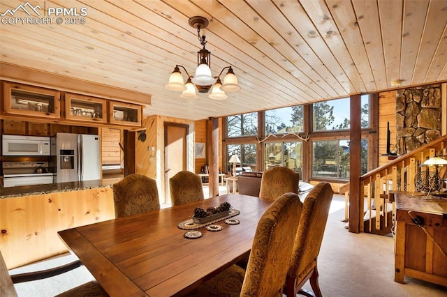 carpeted dining area with wood walls, a chandelier, and wood ceiling