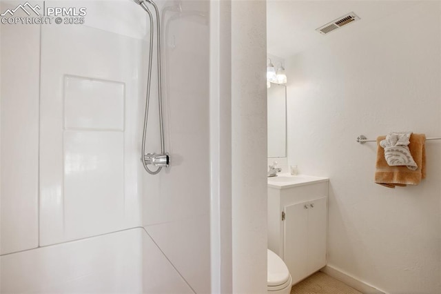 bathroom featuring toilet, a shower, and vanity