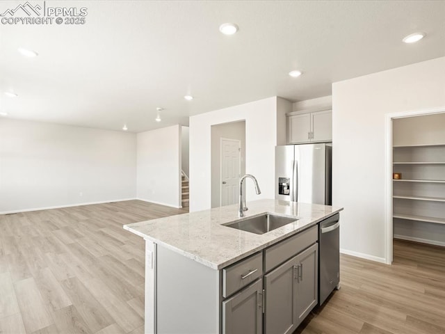 kitchen featuring a kitchen island with sink, sink, gray cabinets, and appliances with stainless steel finishes