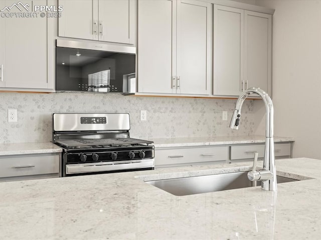 kitchen with light stone counters, sink, tasteful backsplash, and appliances with stainless steel finishes