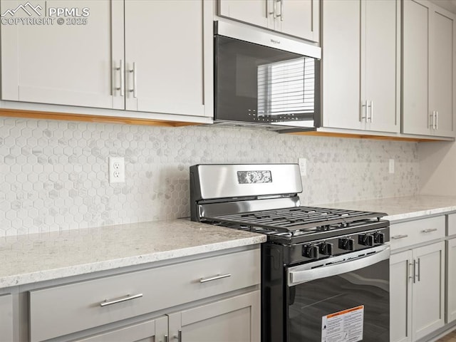 kitchen with tasteful backsplash, gas stove, and light stone counters