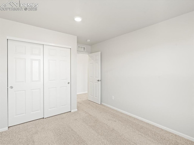 unfurnished bedroom featuring light colored carpet and a closet