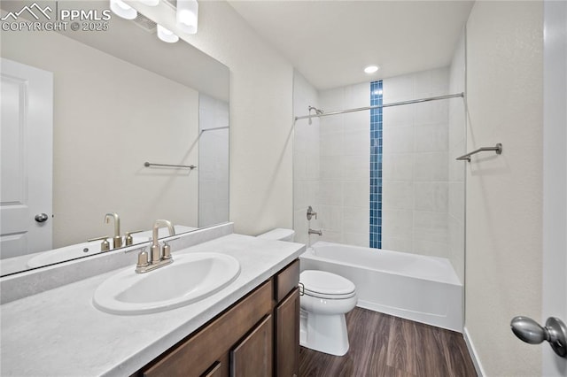 full bathroom featuring hardwood / wood-style floors, tiled shower / bath combo, toilet, and vanity