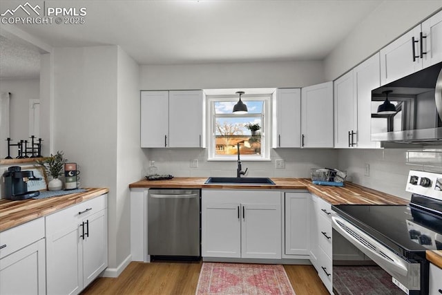 kitchen with white cabinets, appliances with stainless steel finishes, and butcher block countertops