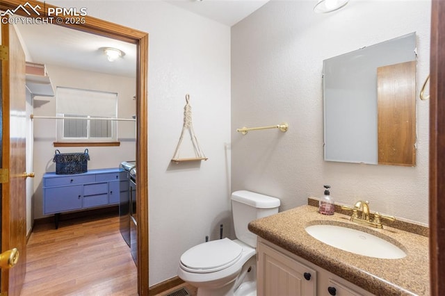 bathroom featuring toilet, vanity, and hardwood / wood-style flooring