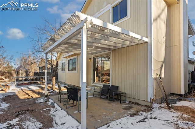 view of snow covered exterior featuring a pergola, a trampoline, and a patio area