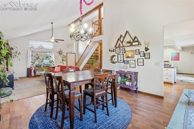 dining space featuring hardwood / wood-style floors, ceiling fan with notable chandelier, and high vaulted ceiling