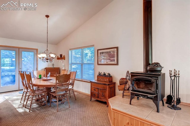 dining room featuring vaulted ceiling, a wood stove, an inviting chandelier, and carpet flooring