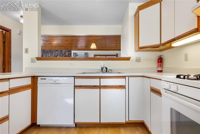 kitchen featuring white cabinetry, sink, light hardwood / wood-style flooring, and white appliances