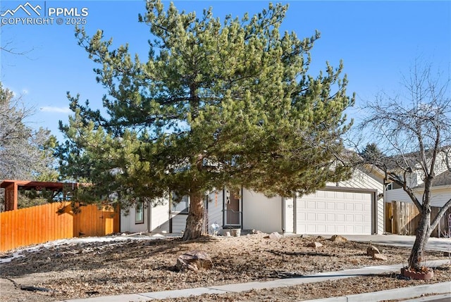 view of property hidden behind natural elements featuring a garage