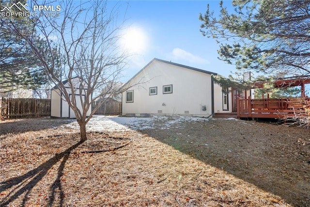 back of property featuring a wooden deck and a storage unit