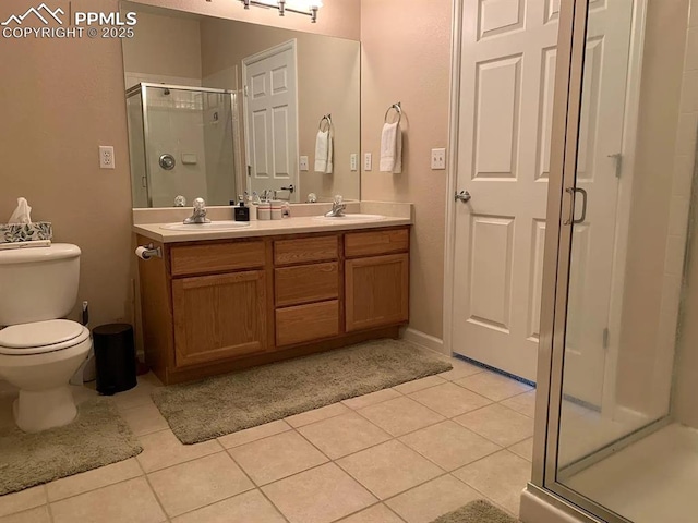 bathroom with a shower with shower door, toilet, vanity, and tile patterned flooring