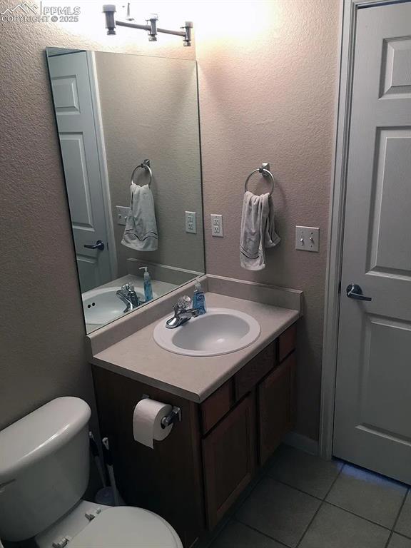 bathroom featuring toilet, vanity, and tile patterned flooring