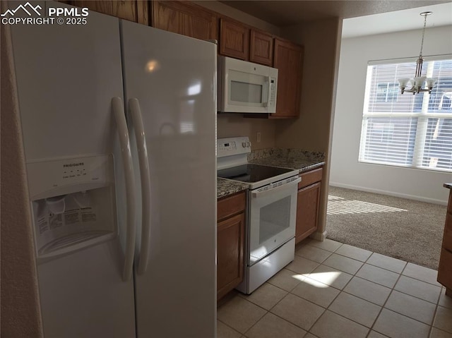 kitchen featuring pendant lighting, white appliances, dark stone countertops, a notable chandelier, and light colored carpet