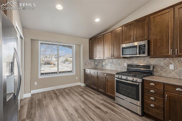 kitchen featuring dark brown cabinets, stainless steel appliances, and lofted ceiling