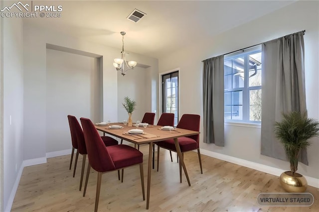 dining space with a wealth of natural light, light hardwood / wood-style floors, and a notable chandelier