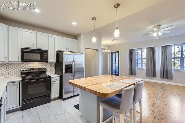 kitchen with pendant lighting, black appliances, decorative backsplash, a kitchen bar, and white cabinets