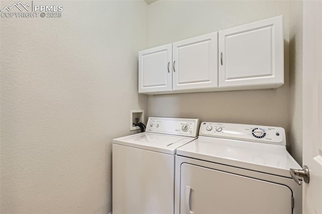 clothes washing area featuring cabinets and washer and clothes dryer