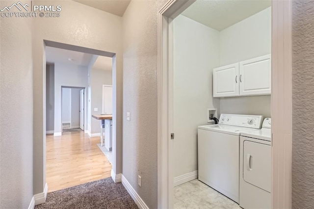 laundry room featuring washer and dryer, light carpet, and cabinets