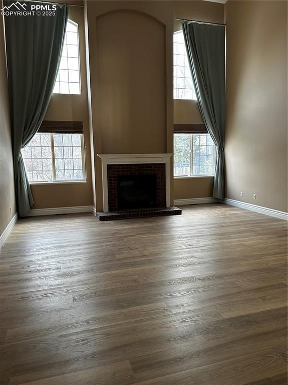 unfurnished living room with hardwood / wood-style flooring, a fireplace, and a high ceiling