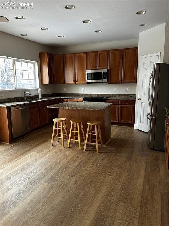 kitchen featuring a kitchen island, appliances with stainless steel finishes, a breakfast bar, dark hardwood / wood-style floors, and sink