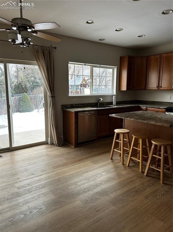 kitchen featuring hardwood / wood-style flooring, a healthy amount of sunlight, dishwasher, and a breakfast bar area