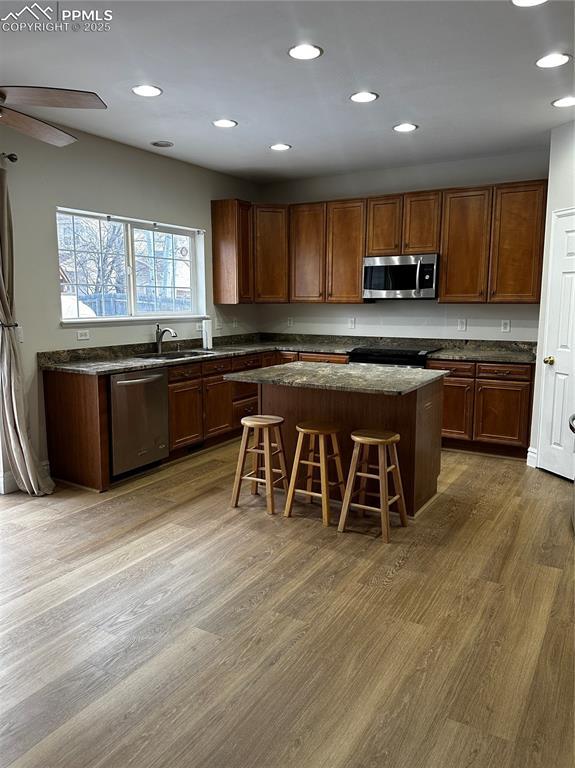 kitchen featuring sink, a breakfast bar area, appliances with stainless steel finishes, hardwood / wood-style floors, and a kitchen island