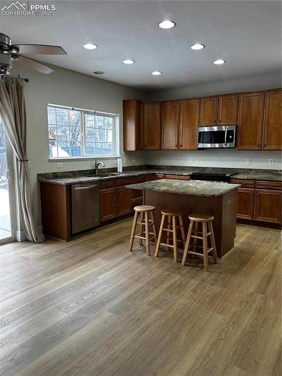 kitchen with wood-type flooring, stainless steel appliances, a kitchen breakfast bar, and a center island