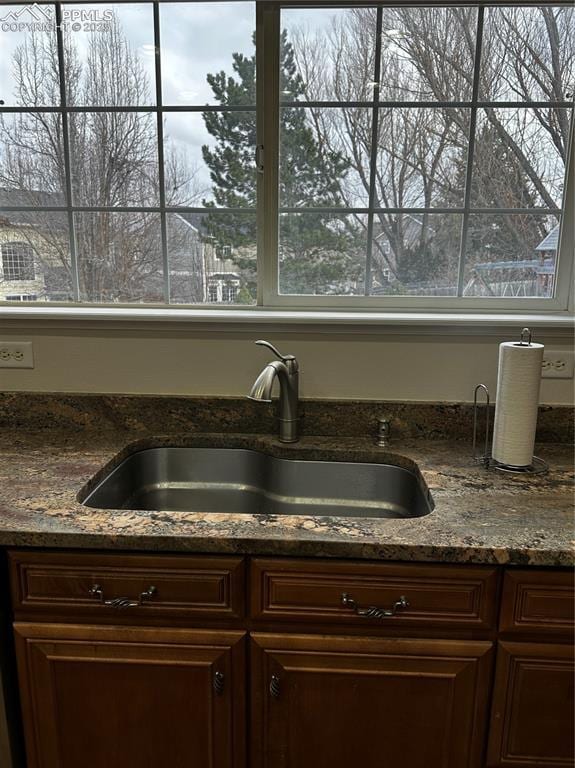 room details featuring dark brown cabinetry, sink, and dark stone counters