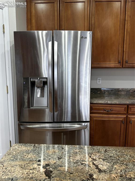 kitchen with dark stone countertops and stainless steel refrigerator with ice dispenser