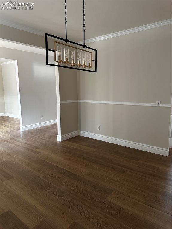 unfurnished dining area with ornamental molding and dark hardwood / wood-style flooring