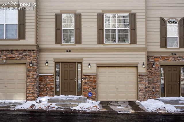 snow covered property entrance featuring a garage