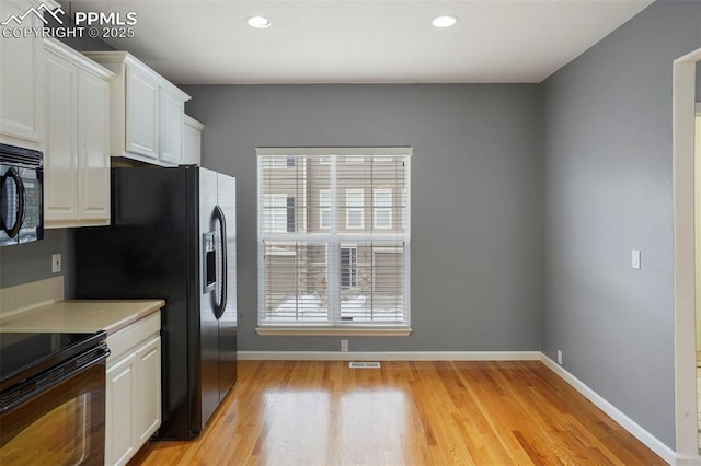 kitchen with white cabinetry, light hardwood / wood-style flooring, and black appliances