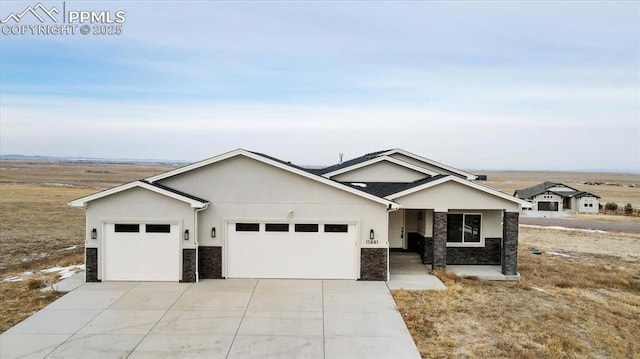 single story home with a garage, stone siding, driveway, and stucco siding