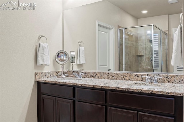 bathroom with a shower with shower door and vanity