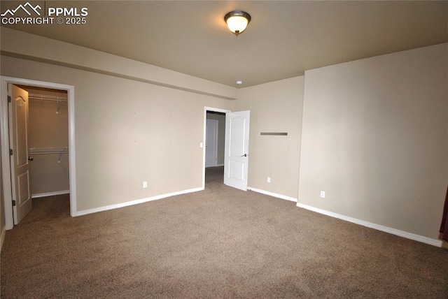 unfurnished bedroom with dark colored carpet, a closet, and a spacious closet