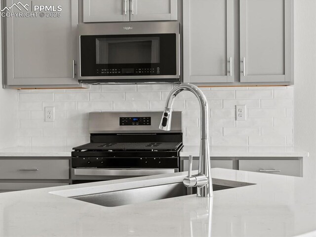 10434 Devoncove Dr, Peyton, CO 80831 - kitchen featuring decorative backsplash, stainless steel microwave, and gray cabinets