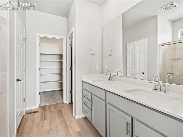 10434 Devoncove Dr, Peyton, CO 80831 - full bathroom featuring a sink, visible vents, wood finished floors, and a stall shower