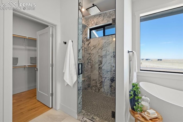 bathroom featuring wood-type flooring and shower with separate bathtub