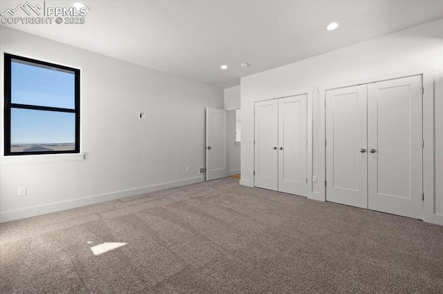 unfurnished bedroom featuring carpet floors and multiple closets