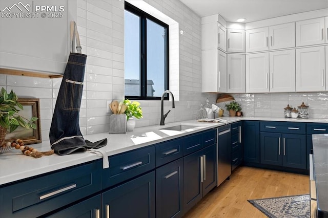 kitchen featuring blue cabinetry, light wood-type flooring, sink, and white cabinets