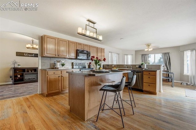 kitchen with decorative light fixtures, stainless steel appliances, and light hardwood / wood-style flooring