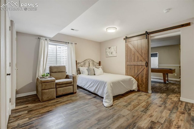 bedroom with hardwood / wood-style floors, a barn door, and billiards