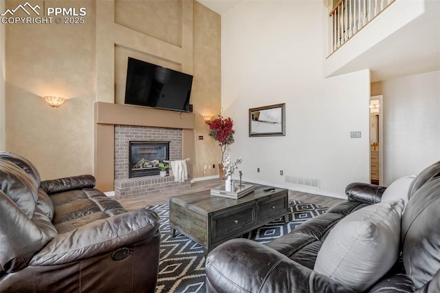 living room with a fireplace, wood-type flooring, and a high ceiling