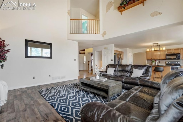 living room with beamed ceiling, a towering ceiling, and dark hardwood / wood-style floors