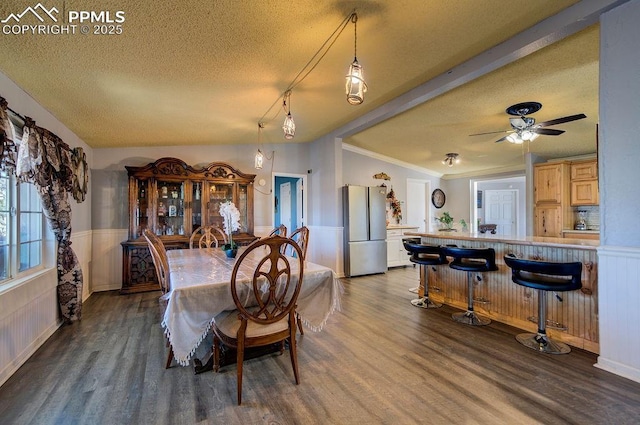 dining room with dark wood-type flooring, a textured ceiling, ceiling fan, and ornamental molding